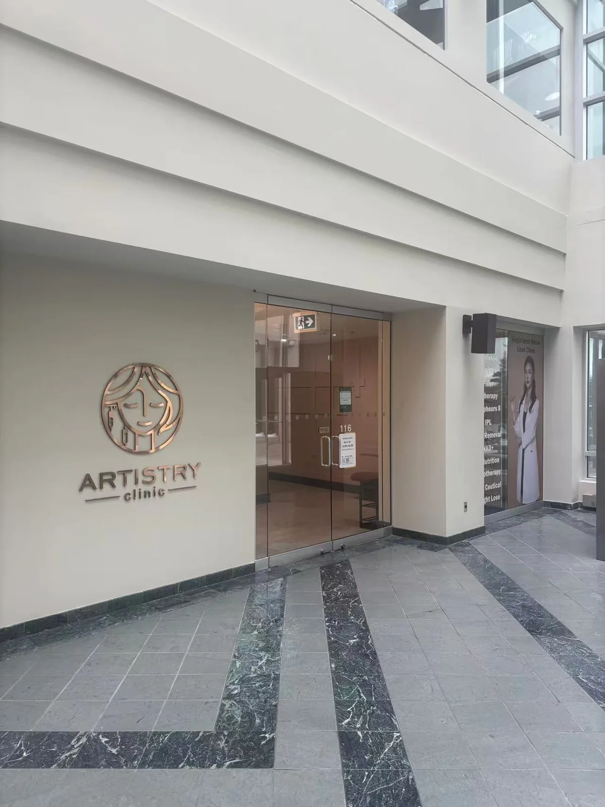 The entrance to Artistry Clinic, Suite 116, with the brand wordmark in brushed copper on a warm neutral wall.