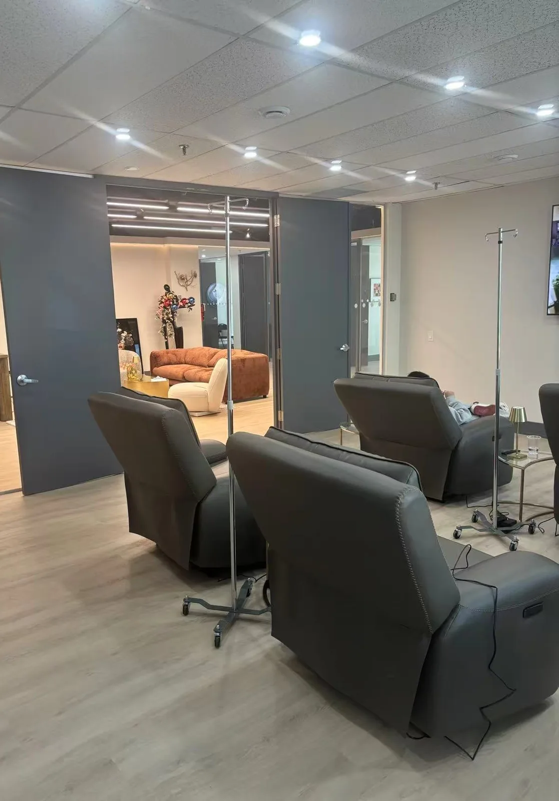 The IV therapy lounge at Artistry Clinic, with reclining leather chairs, drip stands, and brass side lamps.