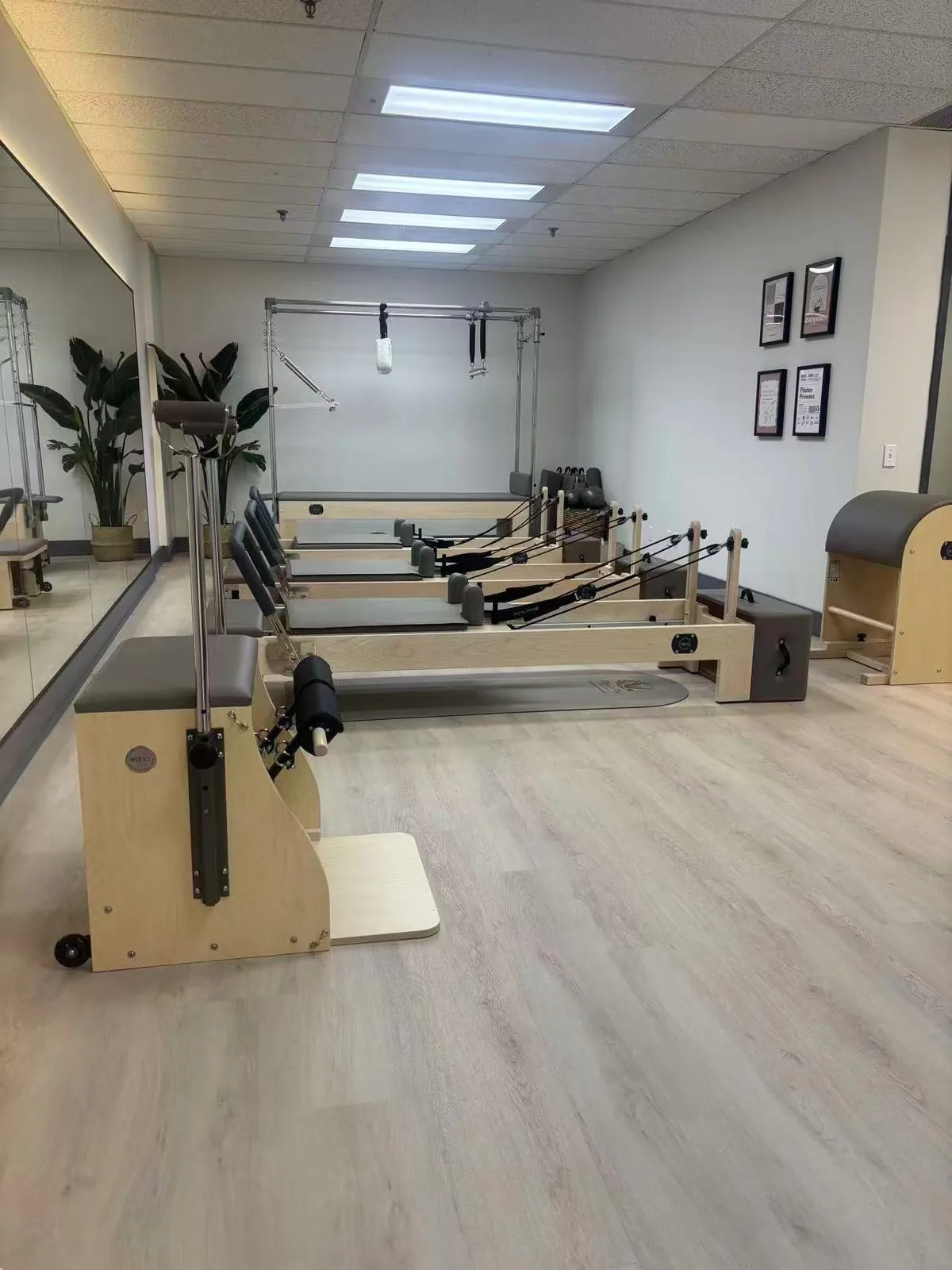 The pilates studio at Artistry Clinic, with reformer equipment, a mirrored wall, and natural light.