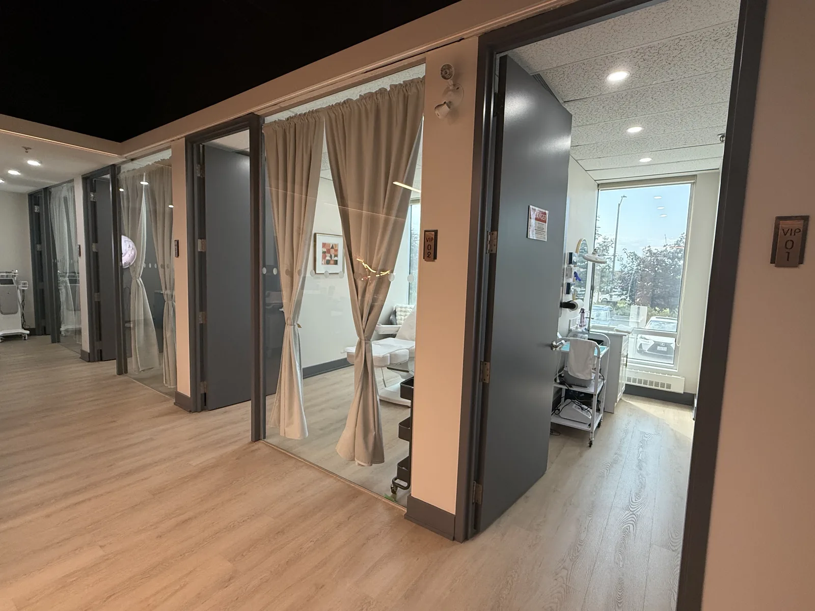 A corridor of private treatment suites at Artistry Clinic, each with a solid door and floor-length curtains.