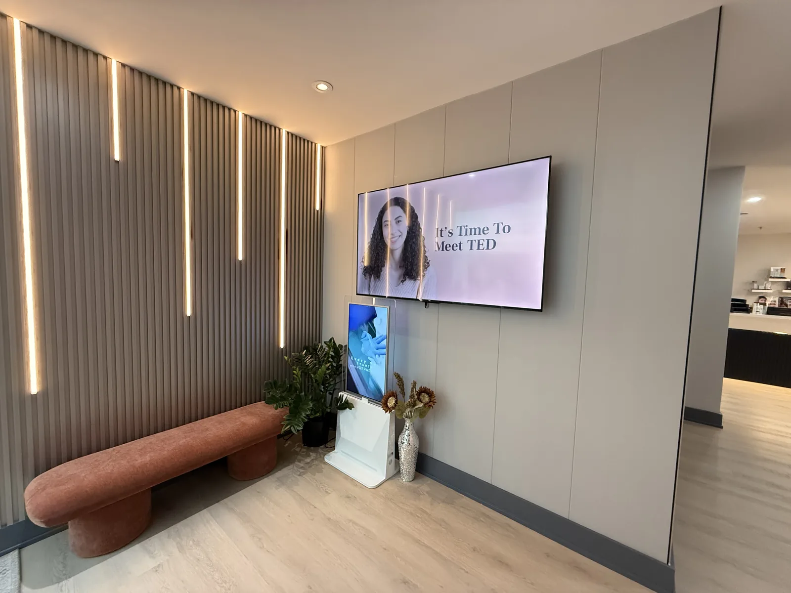 The waiting area at Artistry Clinic, with a curved terracotta bench beneath a fluted wall with vertical light lines.