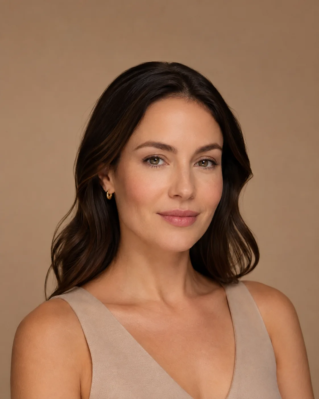 A woman photographed against a warm neutral background at Artistry Clinic.